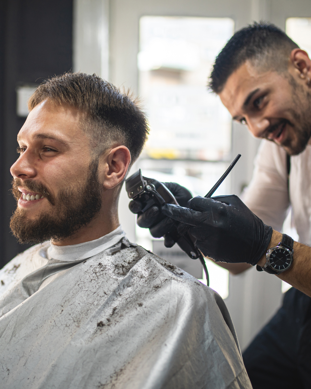 Cliente sorrindo enquanto o barbeiro finaliza o corte